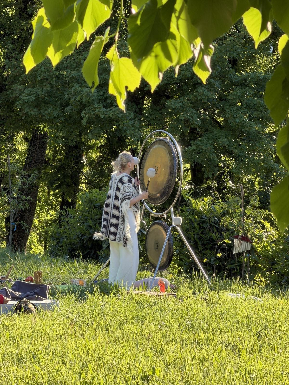 Elena Bianchini con i gong in un prato soleggiato durante il bagno di suoni a Montese