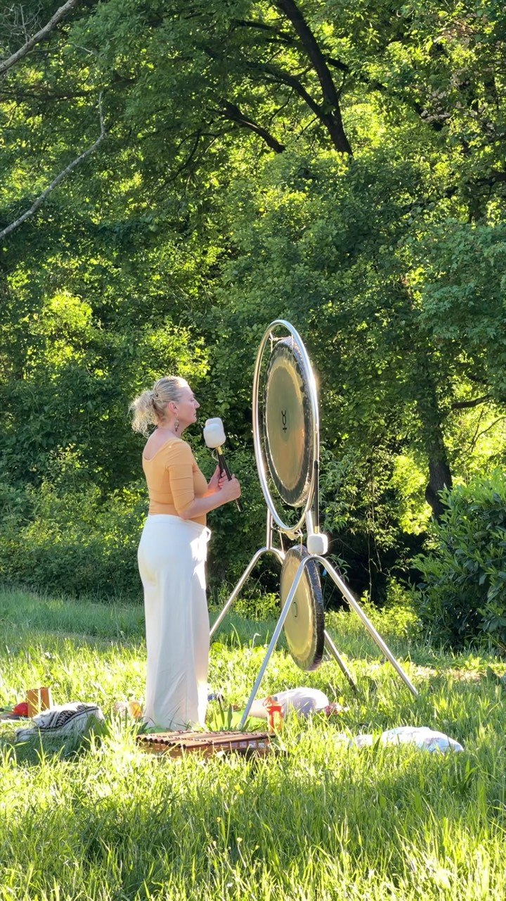 Elena suona il gong durante un bagno di suoni nel prato, ripreso al rallentatore